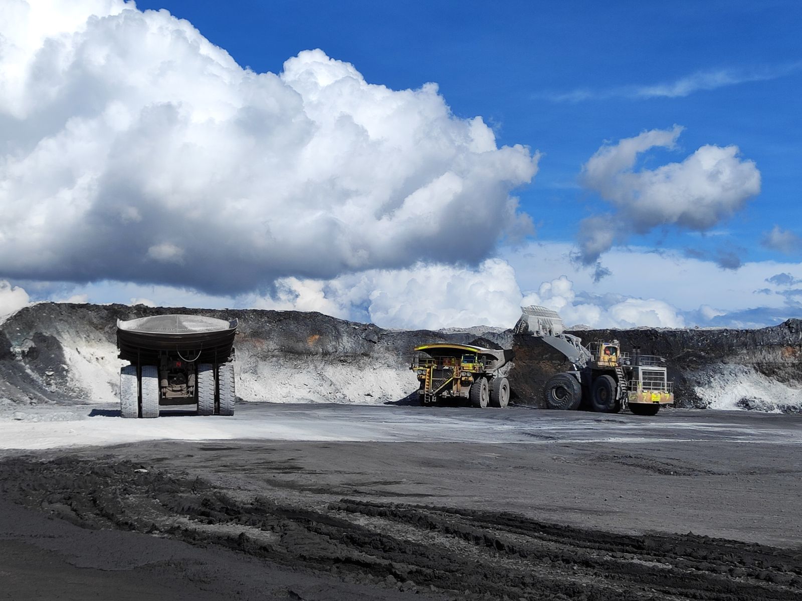 Haul trucks and loader working in an open pit mine